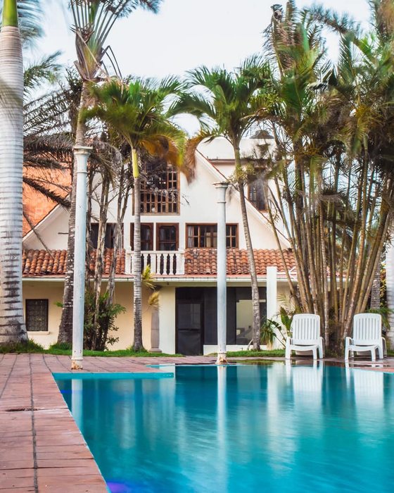 Casa blanca con alberca privada rodeada de palmeras