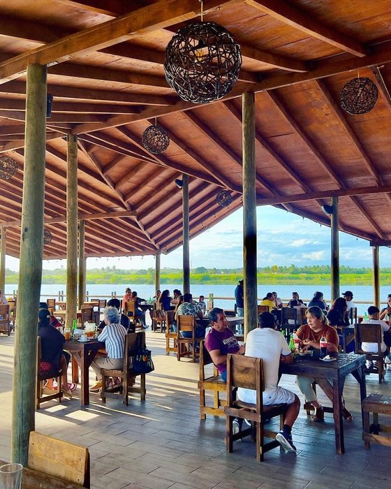 Restaurante bajo palapa de madera con mesas y vista abierta al río